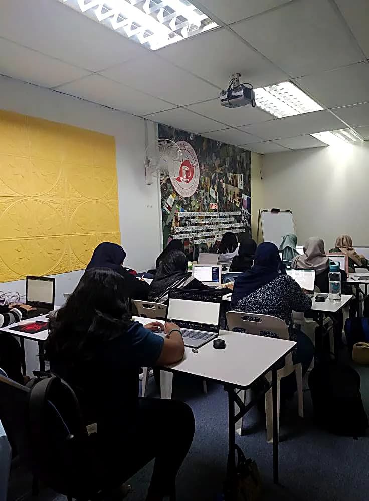 Students at their laptops in a full academy classroom session